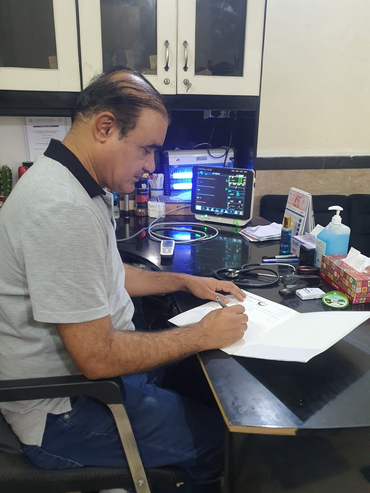Prof. Dr Muhammad Bilal reviewing patient notes in his clinic office